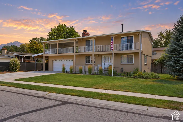 Two-story stucco exterior, upper-level balcony, ground-level covered patio, integrated two-car garage, and a concrete driveway
