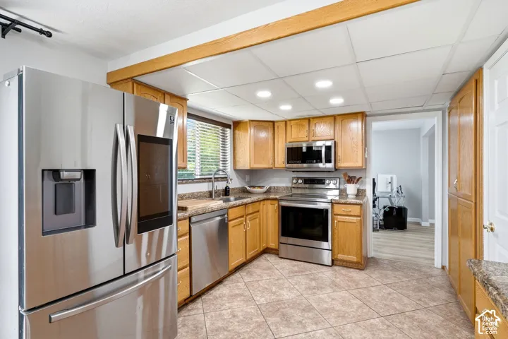 Kitchen featuring stainless steel appliances, wood cabinetry, tile flooring, and recessed lighting