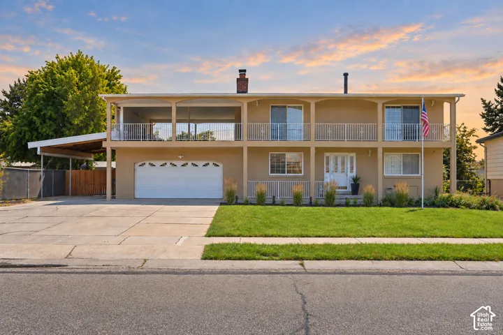 Two-story residence featuring a carport, integrated garage, and a full-width upper-level balcony with white railings