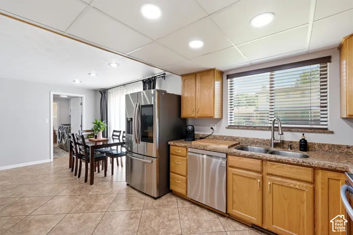 Kitchen featuring wood cabinetry, stainless steel appliances, a dual basin sink, and patterned countertops
