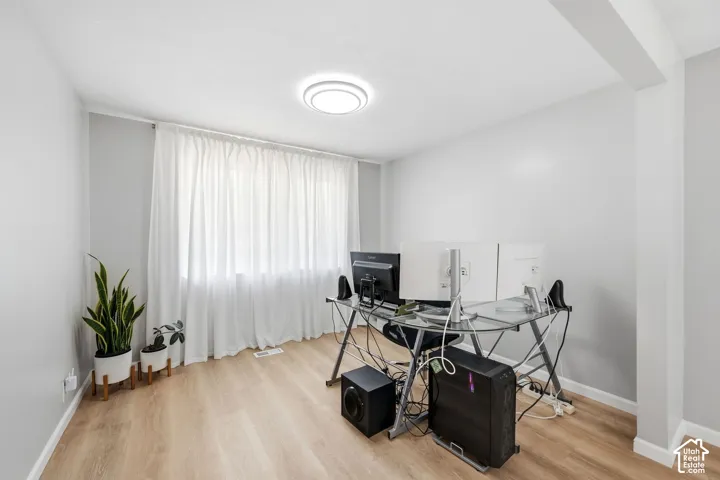 Light wood-finish flooring, recessed ceiling light, and a large window with privacy coverings