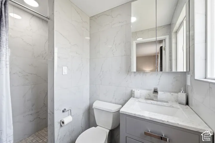 Shower with mosaic tile floor, white subway tile walls, corner vanity with integrated sink, chrome faucet, and mirrored medicine cabinet