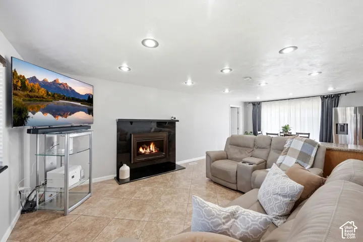 Recessed lighting and tile flooring complement the built-in fireplace with a black surround