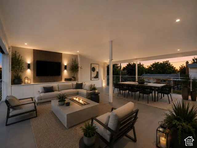Expansive covered patio featuring a built-in media wall with integrated lighting, a concrete fire pit, and ample space for dining