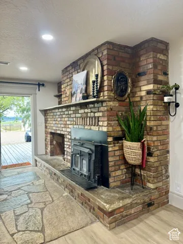 Brick fireplace with a built-in wood-burning insert, an extended stone hearth, and a mantel shelf