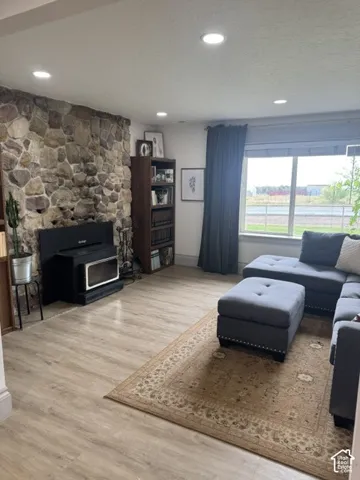Stone accent wall with built-in wood-burning stove and wood-finish flooring