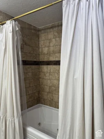 Jetted tub with tile surround, featuring a decorative mosaic accent band