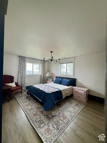 Wood-finish flooring, white walls, and a black chandelier
