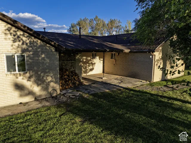 Brick exterior with a covered patio and a shingle roof