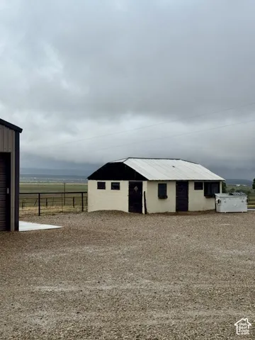 Gravel lot with a detached structure featuring multiple windows and a metal roof