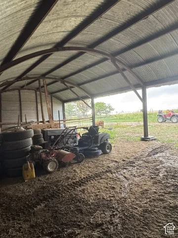 Corrugated metal roof, open-sided structure, metal support beams, dirt ground