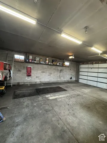 Concrete flooring with integrated drainage, block wall construction, and fluorescent overhead lighting