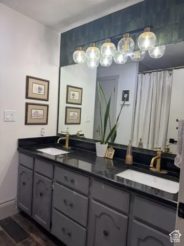 Dual vanity with dark stone countertop, undermount sinks, and gold-tone fixtures