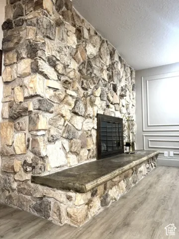 Stone fireplace with a hearth, wood-finish flooring, and decorative wall molding