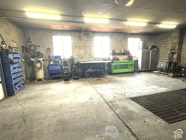 Concrete block walls, multiple windows, overhead fluorescent lighting, concrete flooring, and an integrated floor grate