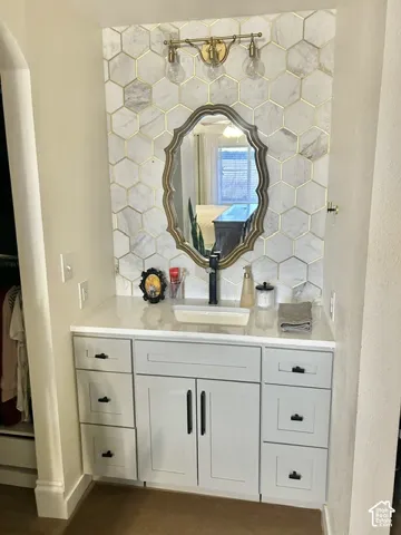 White vanity with black pulls, undermount rectangular sink, and gold-framed mirror