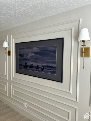 Decorative wall molding with picture frame paneling, recessed wall panel for artwork, and dual wall sconces with drum shades