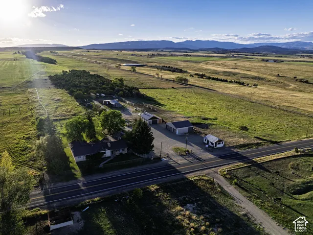 Expansive rural property featuring multiple structures, open fields, and distant mountain ranges