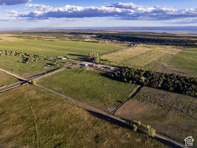 Expansive land featuring agricultural fields, paved roads, and scattered outbuildings