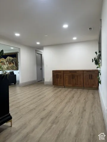 Recessed lighting illuminates wood-finish flooring and a built-in cabinetry unit with multiple storage compartments