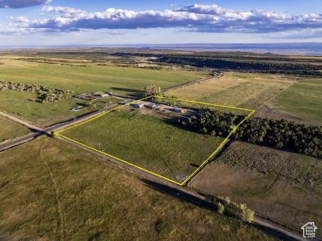 Expansive land parcel with clear boundary lines, featuring multiple structures, open fields, and mature tree lines