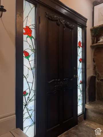 Solid wood entry door with carved detailing, flanked by stained glass sidelights featuring a rose motif