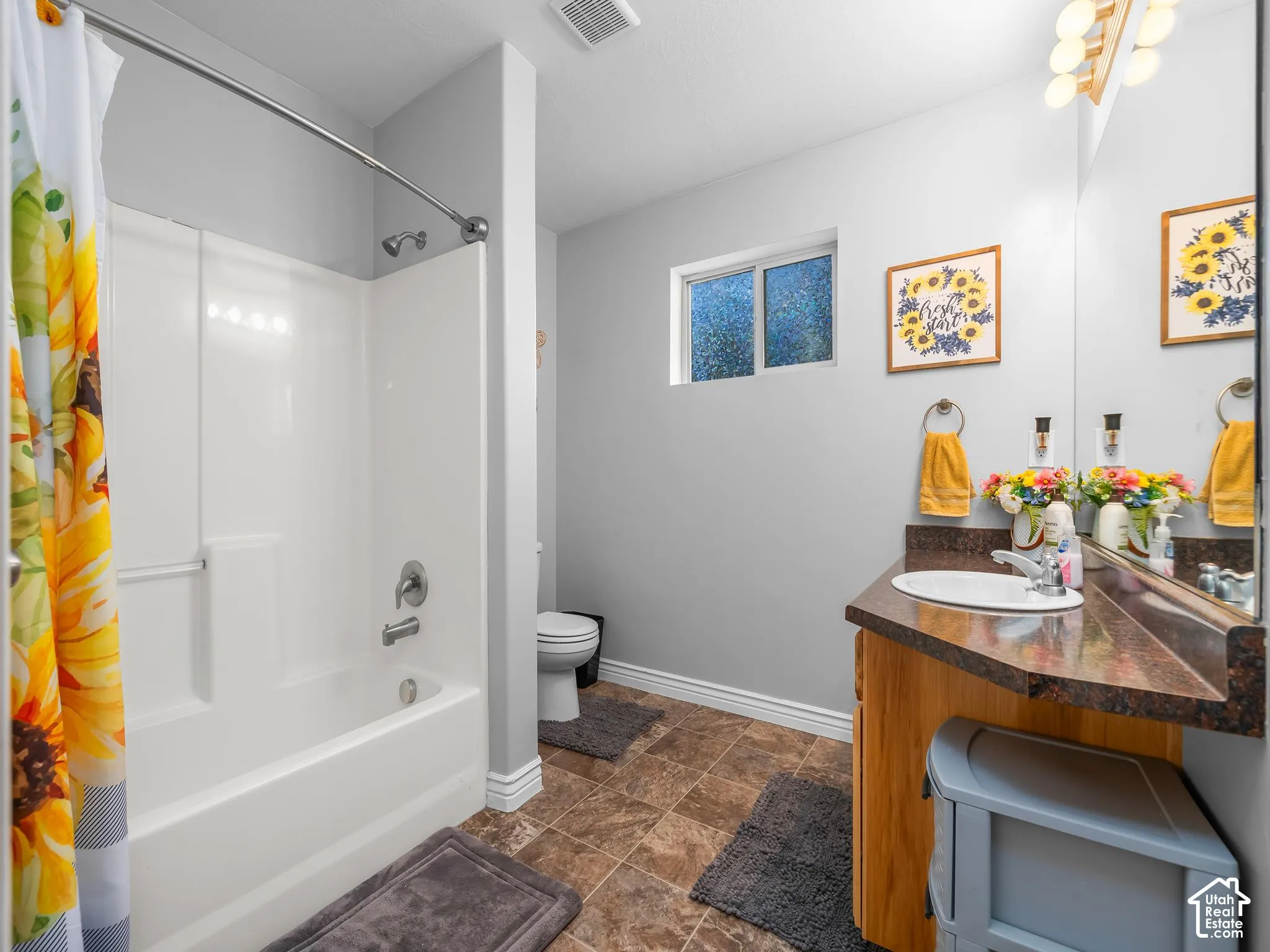 Bathroom featuring a white shower-tub combination, wood-finish vanity with a dark countertop, integrated sink, and an overhead vanity light