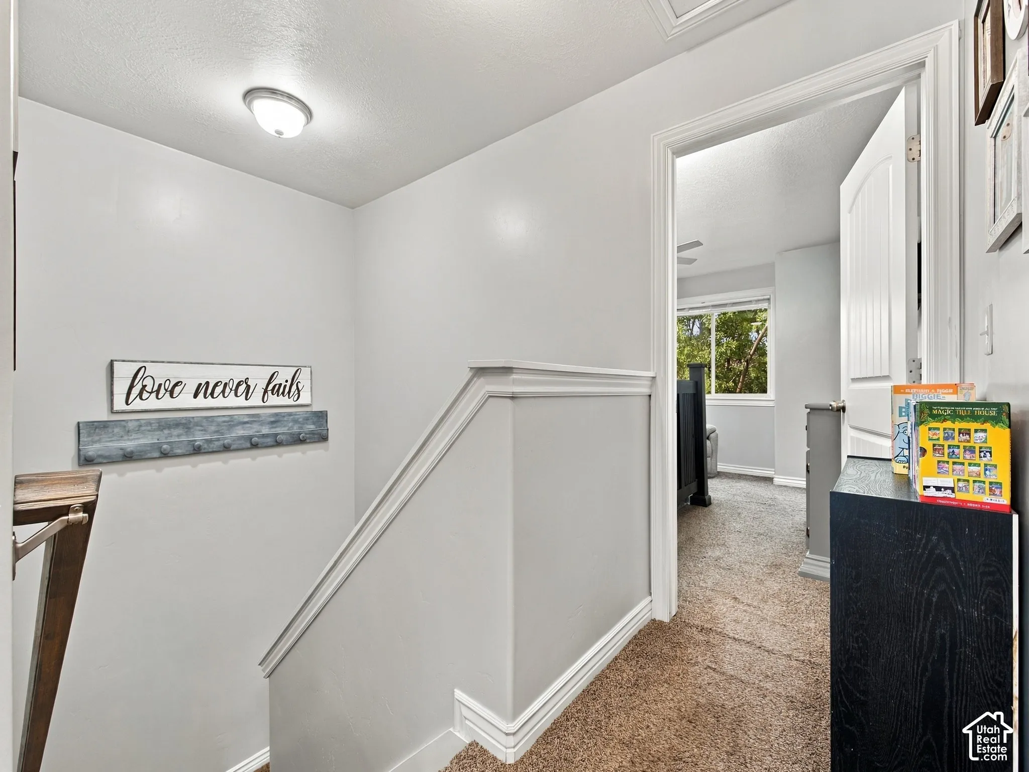 Upper-level hallway with neutral wall paint, carpet flooring, and white trim