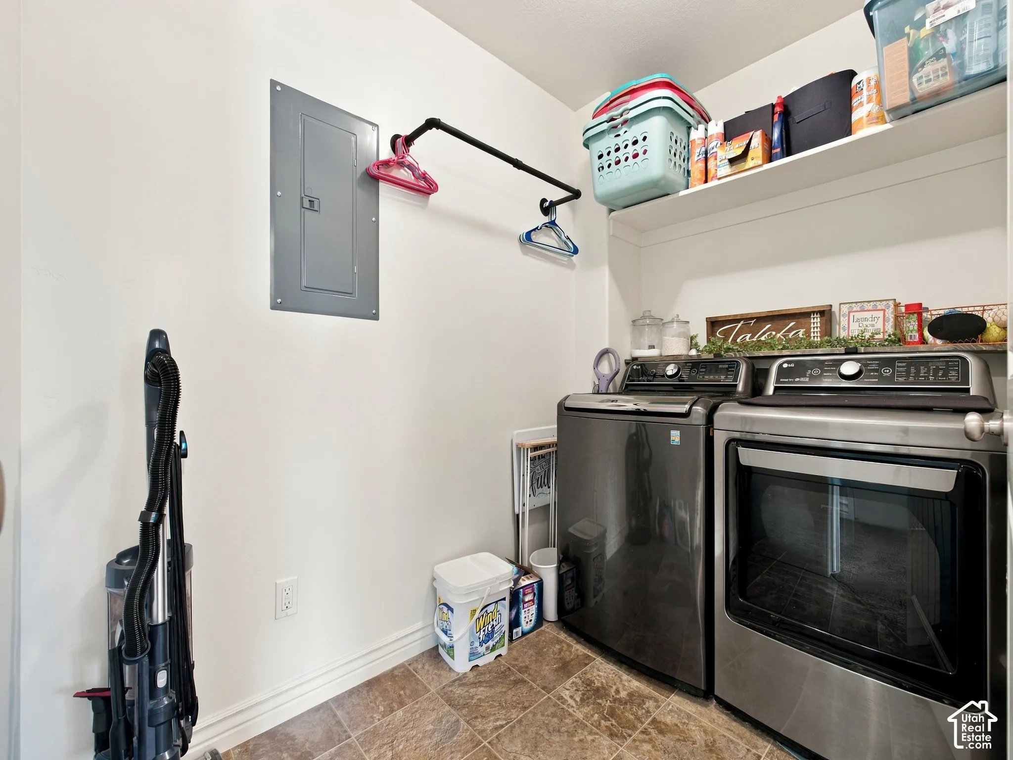Laundry area featuring a built-in shelf, hanging rod, and textured floor tiling