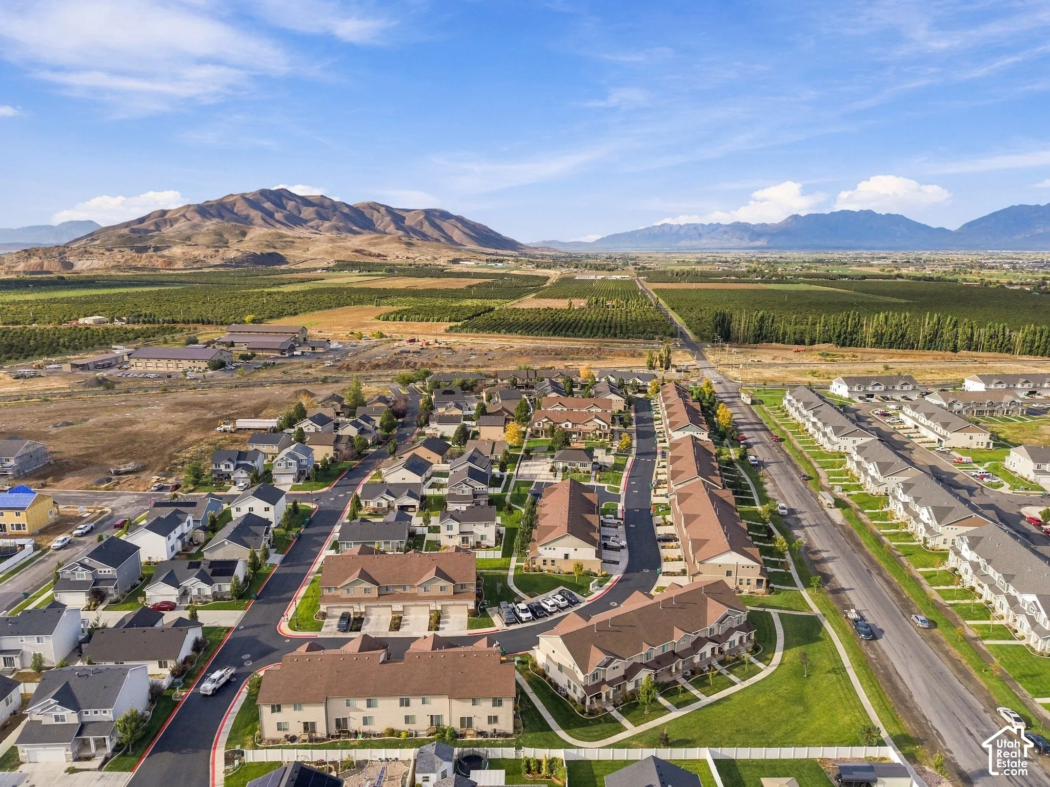 Expansive residential development with a mountain backdrop, surrounded by agricultural land