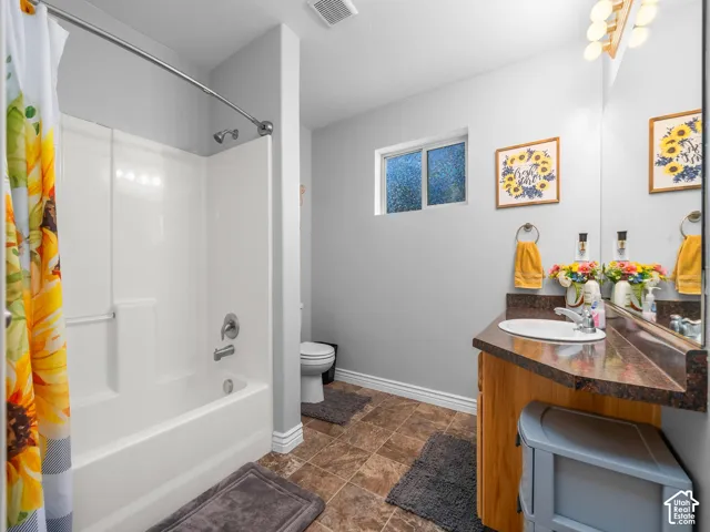 Bathroom featuring a white shower-tub combination, wood-finish vanity with a dark countertop, integrated sink, and an overhead vanity light
