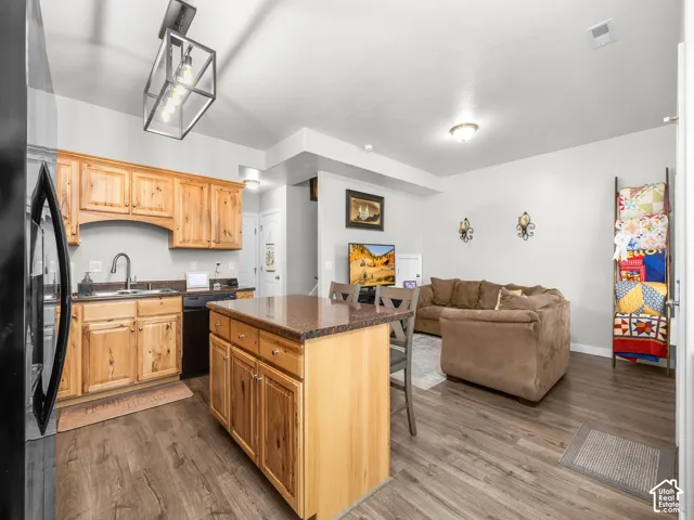 Kitchen with wood-finish cabinetry, dark countertops, and a central island