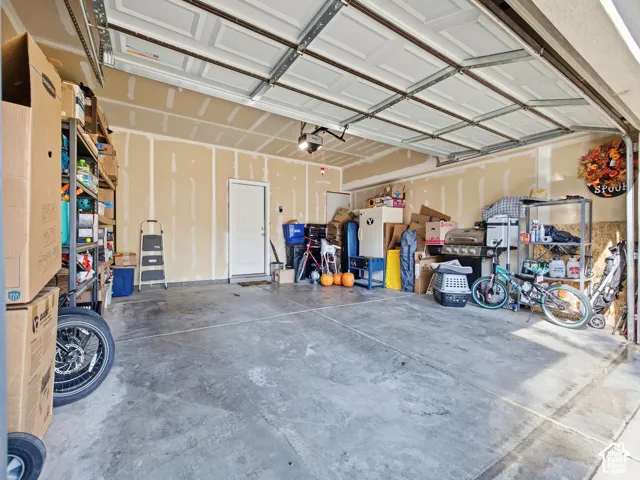 Spacious garage with an overhead automatic door, concrete flooring, and an interior access door
