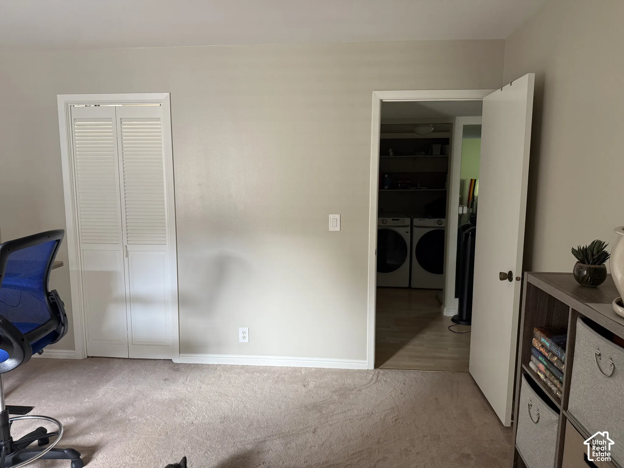 Laundry area with built-in shelving, front-loading washer and dryer, and wood-finish flooring