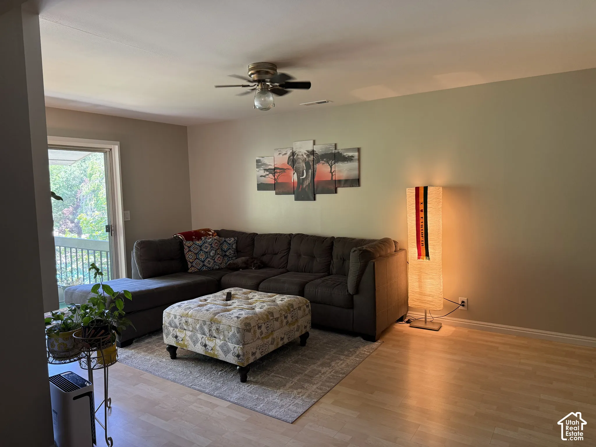 Neutral wall paint, ceiling fan with integrated lighting, wood-finish flooring, and a sliding glass door