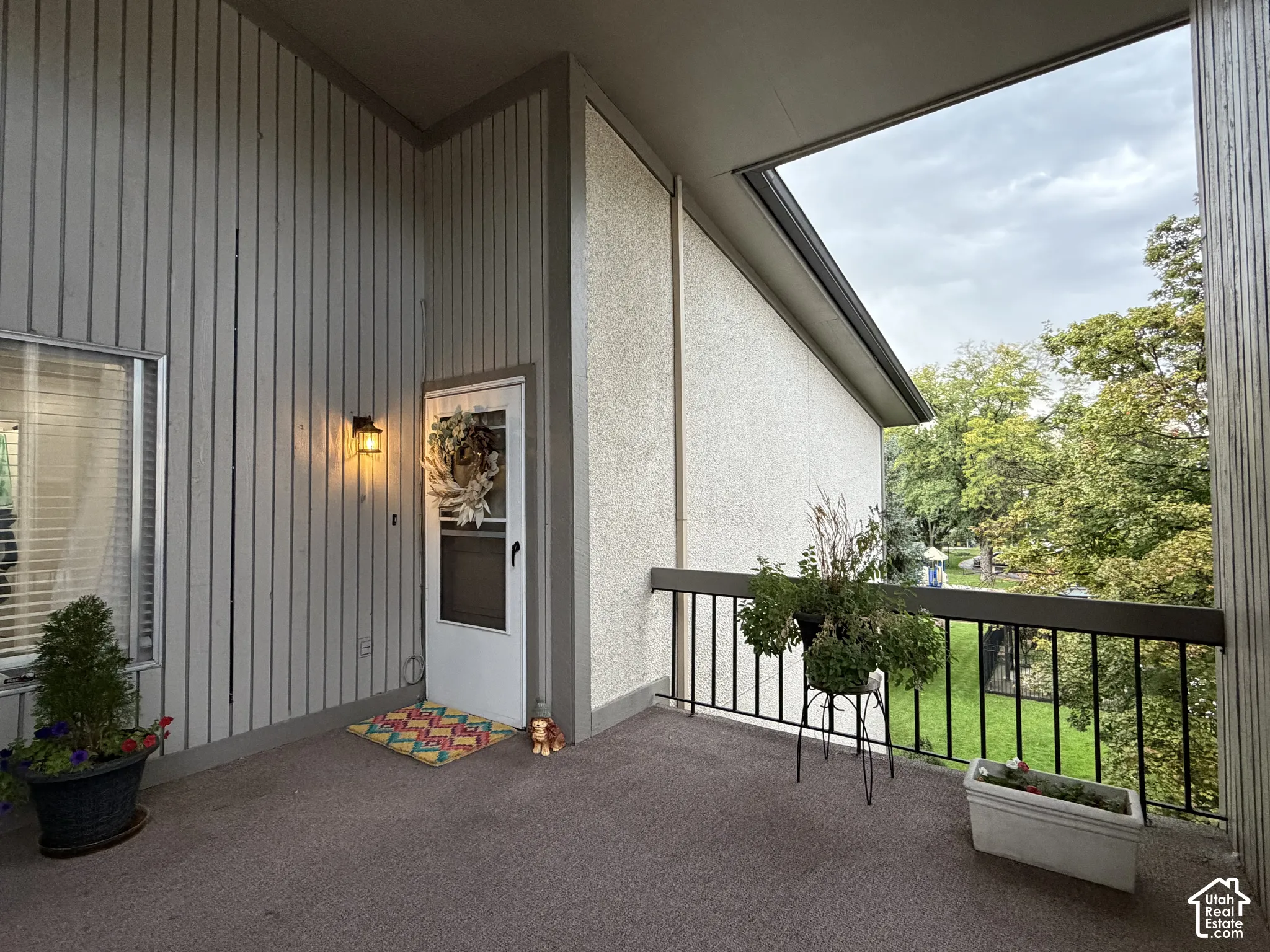 Balcony featuring a dark railing, exterior wall with vertical paneling, and an outdoor light fixture