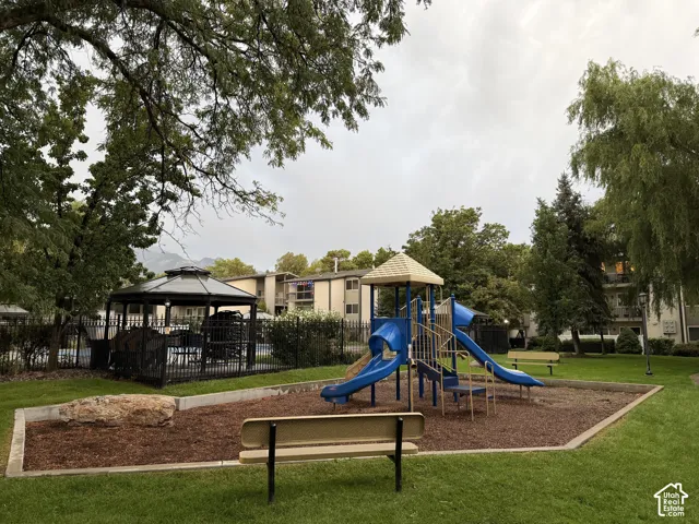 Expansive green space featuring a https://assets.utahrealestate.com/photos/280x210/hb5553198_46f70383561906ef65215a8cab50f1e1_6ab6e2ceed708_edited_1790372243.jpgplayground with slides, a covered gazebo, and mature trees