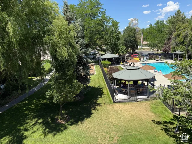 Outdoor recreational area featuring a swimming pool, multiple shaded gazebos, and a paved walking path