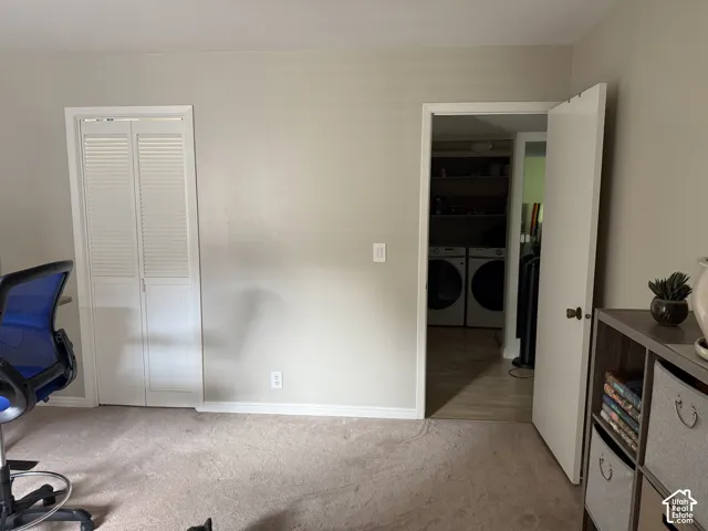 Laundry area with built-in shelving, front-loading washer and dryer, and wood-finish flooring