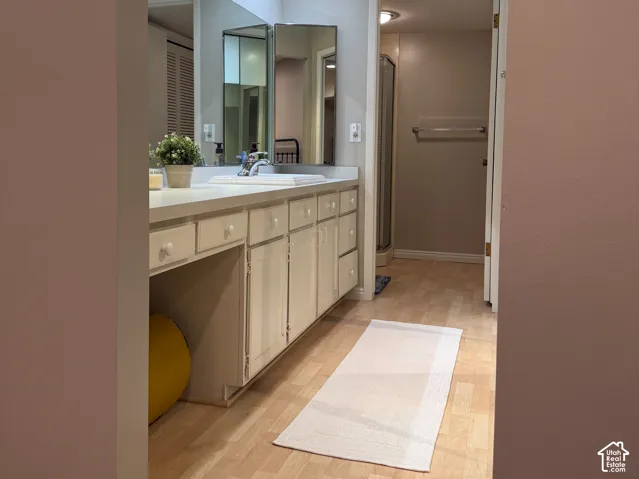 Vanity with extensive counter space and integrated cabinetry, track lighting, and wood-finish flooring