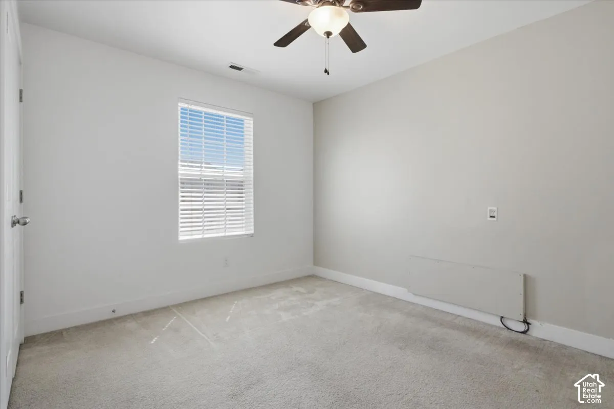 Wall-to-wall carpeting, window with blinds, ceiling fan with integrated lighting, and neutral wall tones