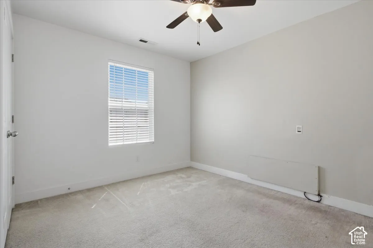 Neutral wall color, carpet flooring, window with blinds, and ceiling fan with integrated lighting