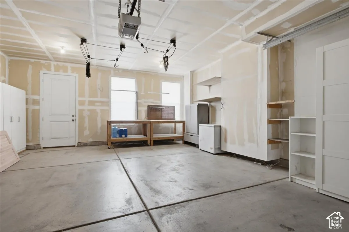Spacious garage featuring a concrete floor, built-in shelving, two windows, and an overhead garage door opener