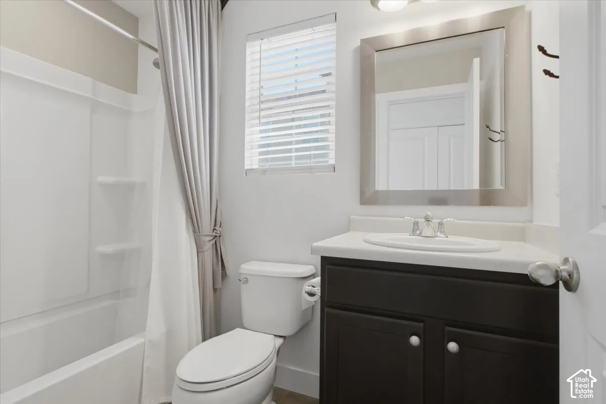 Bathroom featuring a built-in tub with shower, dark wood-finish vanity with countertop, and a framed mirror