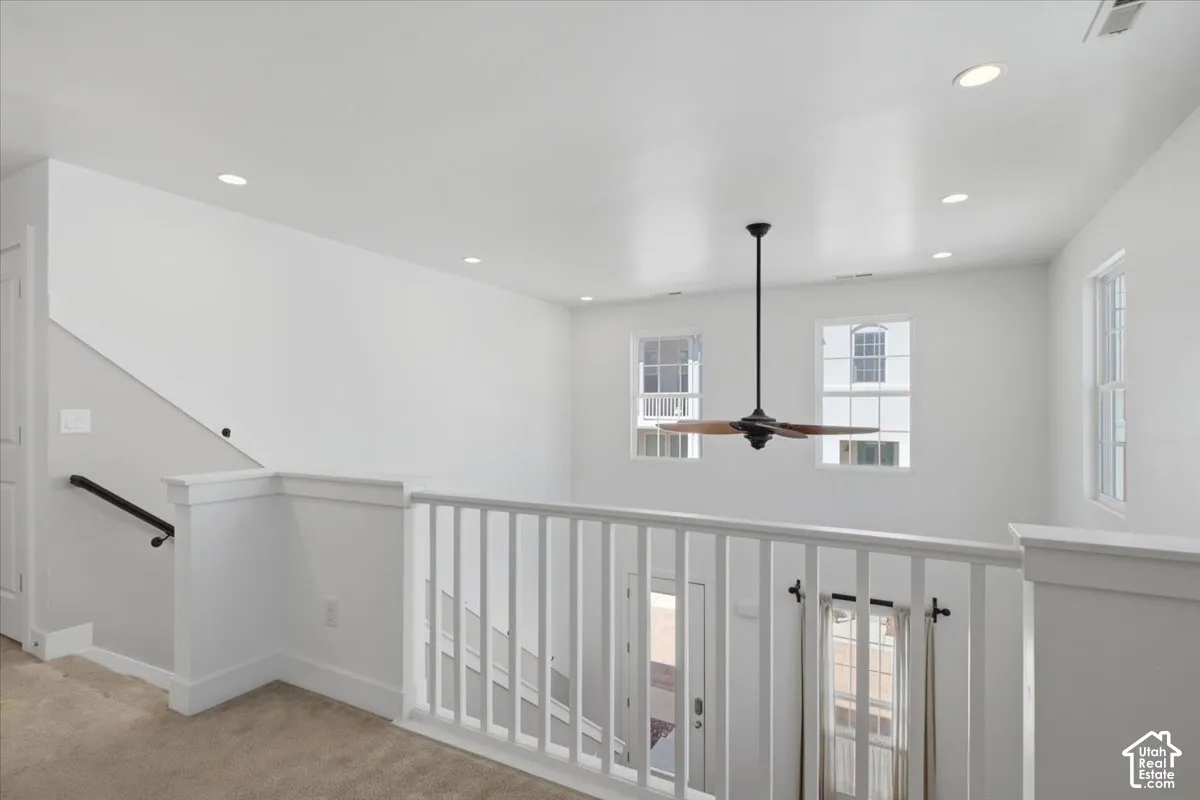 Upper-level landing with white railing, recessed ceiling lighting, and a ceiling fan