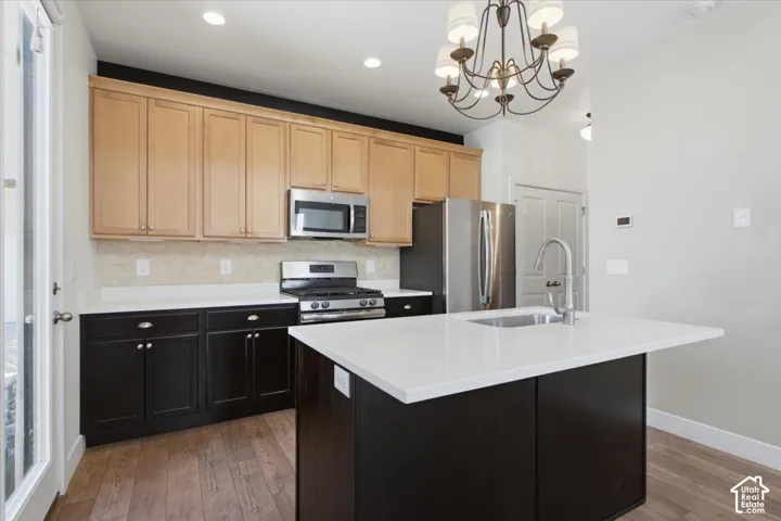 Two-tone cabinetry with stainless steel appliances, white countertops, and a kitchen island with an integrated sink