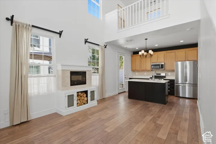 Vaulted ceiling with an upper-level railing, wood-finish flooring, and a fireplace with integrated storage