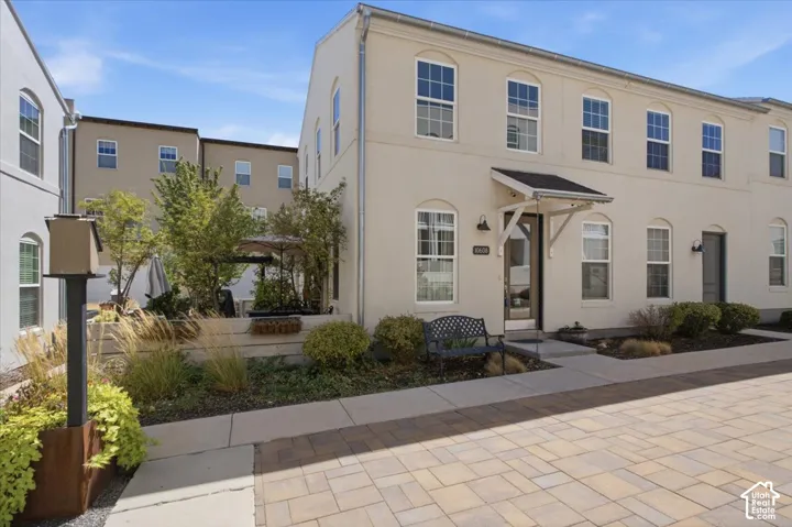 Two-story stucco exterior featuring multiple windows and a covered entryway
