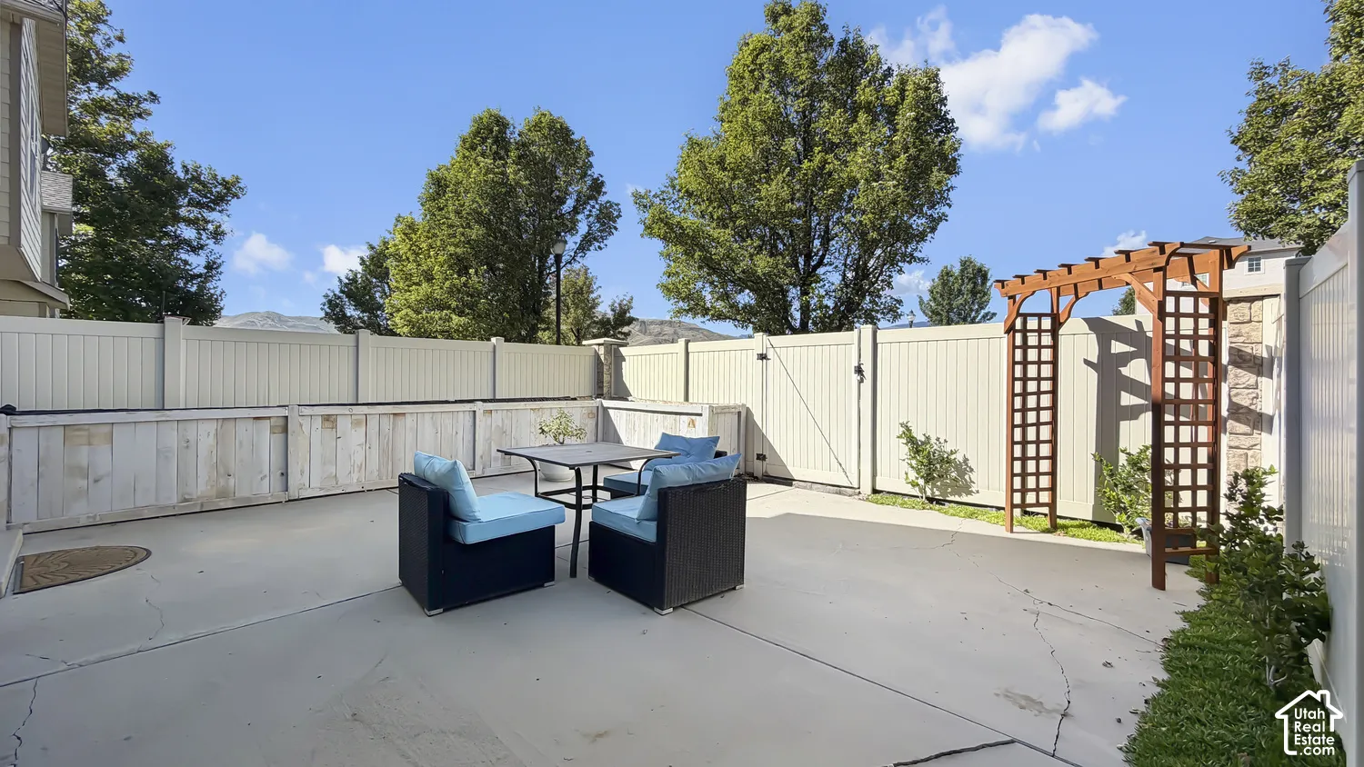 Paved patio area featuring perimeter fencing and a decorative wooden archway