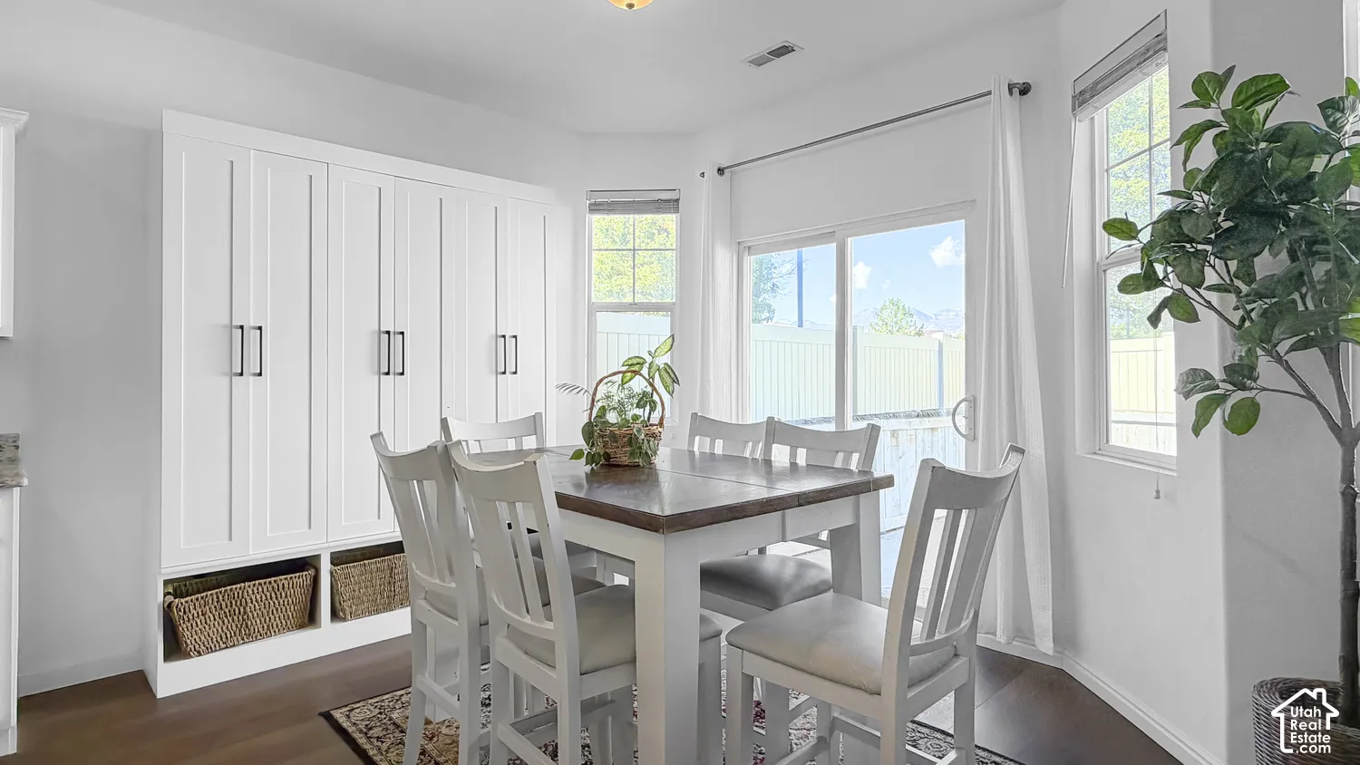 White shaker-style cabinetry with matte black hardware, wood-finish flooring, sliding glass door, and a bay window